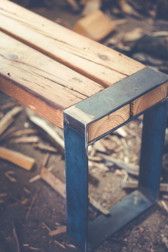 A rustic wooden bench with a metal frame on a textured surface, ideal for outdoor decor.